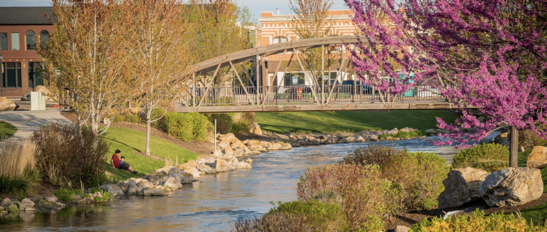 Photograph of the Indian Creek Plaza bridge in downtown Caldwell, Idaho — spring blossoms and the waterway, in the Canyon County area Boise Bug Bombers serves