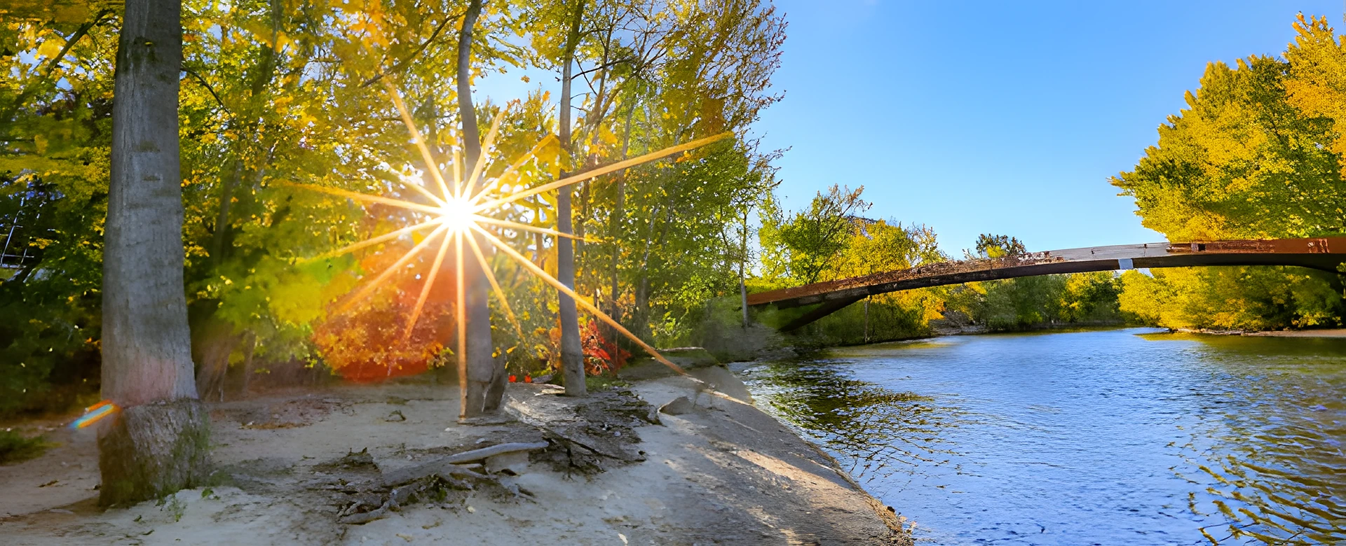 Photograph of the Boise River and pedestrian bridge in Eagle, Idaho — autumn cottonwoods catching the sun, the city served by Boise Bug Bombers